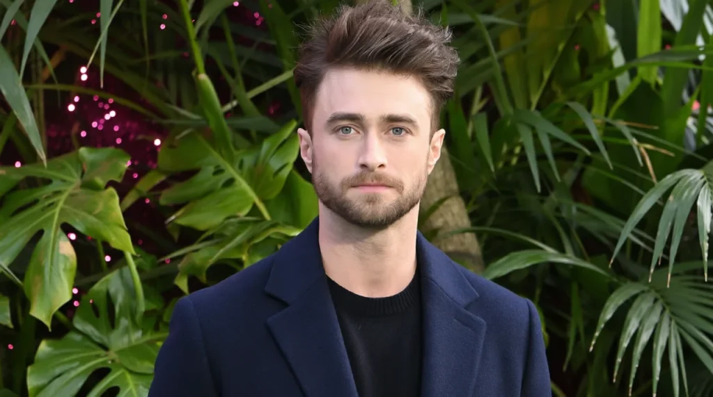 Daniel Radcliffe with short hair, slight stubble, neutral expression.