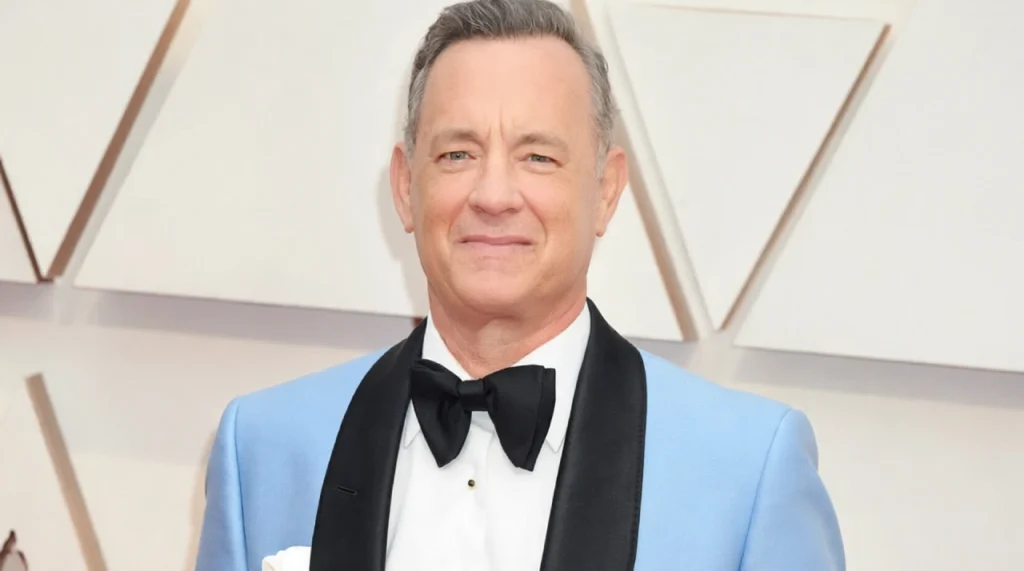 Tom Hanks smiling warmly, wearing a casual shirt.